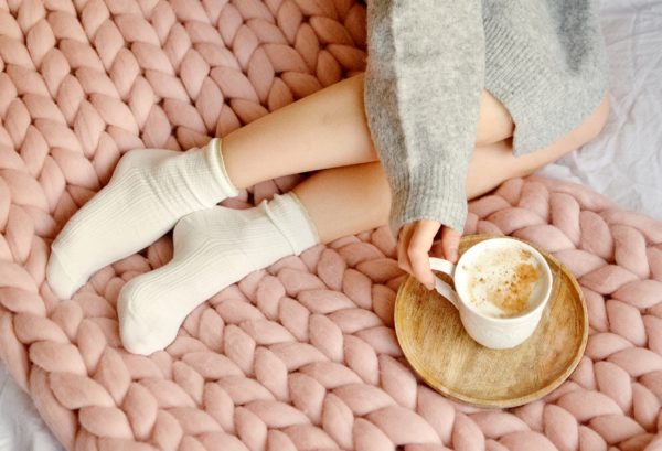 girl having morning coffee in bed laying on chunky knit pink bed runner